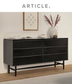 a black dresser sitting on top of a hard wood floor next to a white wall