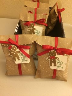 four bags with gingerbreads on them are wrapped in brown paper and red ribbon