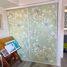 a room with a painting on the wall and an open sliding glass door that has flowers painted on it