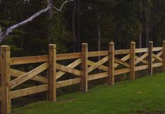 a wooden fence in front of a lush green field