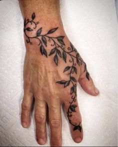 a person's hand with a tattoo on it and leaves in the middle of their palm