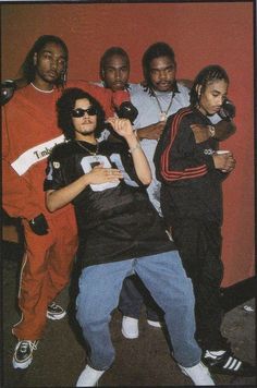 five young men posing together in front of a red wall