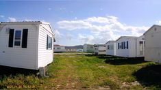 there are many small white houses in the grass near each other and one is empty