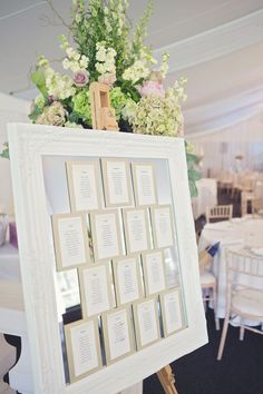 an open book frame with flowers in it on top of a white table cloth covered floor