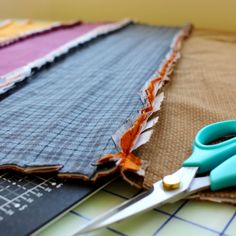 a pair of blue scissors sitting on top of fabric next to some other pieces of cloth