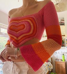 a woman wearing a pink and orange knitted sweater with a heart on the chest