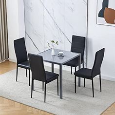 a dining room table with four chairs and a rug on the floor in front of it