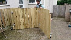 a man is standing behind a wooden fence