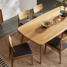 a wooden table with chairs around it and a vase on the table next to it