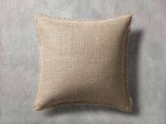 a beige pillow sitting on top of a gray wall