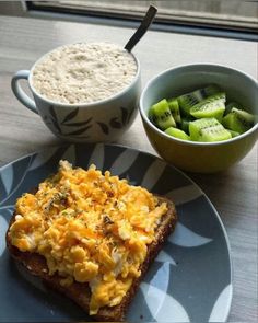 a plate topped with toast next to a bowl of cucumbers and a cup of cereal