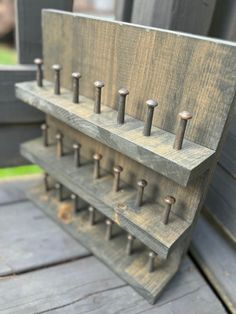 an old wooden rack with many nails on the top and one in the middle is holding several pairs of screws