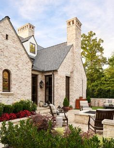 an outdoor patio with chairs and tables in front of a brick house