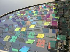 the reflection of an abstract building on top of a car window with colored squares in it