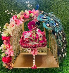 an elaborately decorated peacock sitting on top of a wooden stand with flowers and feathers