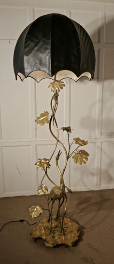 a lamp that is on top of a leafy base with a black and gold shade