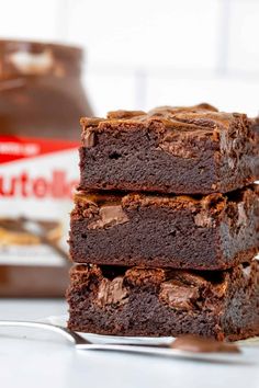 three chocolate brownies stacked on top of each other with a bite taken out of one