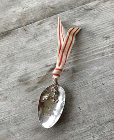 a silver spoon with a red and white ribbon around it on top of a wooden table