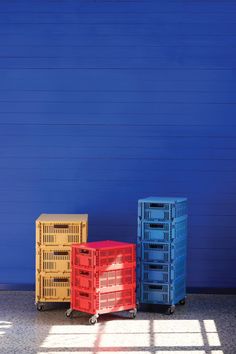 three crates sitting next to each other in front of a blue wall with a shadow on the floor