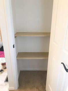 an empty walk in closet next to a door with shelves on the wall and carpeted floor