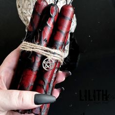 a hand holding three red and black candles