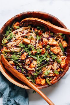 a bowl filled with noodles and vegetables on top of a marble countertop next to chopsticks