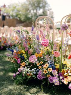 an arrangement of colorful flowers on the ground at a wedding ceremony with chairs in the background