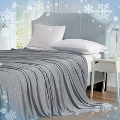 a bed covered in a blanket and pillows with snowflakes on the wall behind it