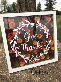 a sign that says give thanks on it in front of a tree with paper flowers