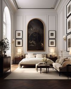 an elegant bedroom with white walls and wood flooring, framed artwork on the wall