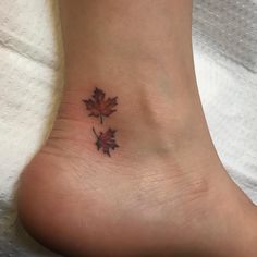 a small leaf tattoo on the foot of a woman's foot, with two leaves in it