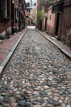 a cobblestone street is lined with brick buildings