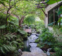 a garden with rocks, plants and water in the foreground is an entry way to a house