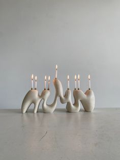 four white candles are lined up in the shape of elephants with long, slender legs