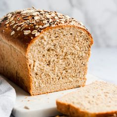 a loaf of bread sitting on top of a white cutting board next to a piece of bread