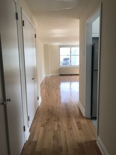 an empty room with hard wood flooring and sliding doors leading to another room in the background