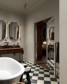 a bathroom with checkered flooring and three mirrors on the wall above the bathtub