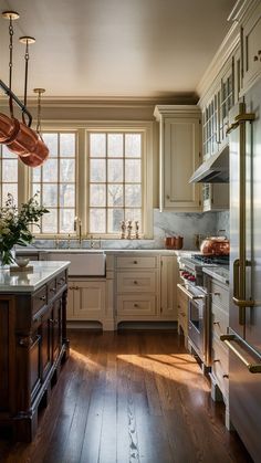 a large kitchen with wooden floors and white cabinets, an island in the middle is surrounded by pots and pans