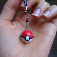 a hand holding a red and white pokeball charm