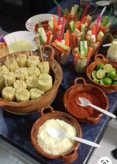 there are many different foods in bowls on the table with toothpicks and dips