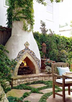 an outdoor fireplace surrounded by greenery and chairs