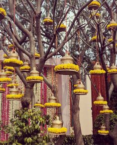 many yellow and white bells hanging from trees in front of a building with flowers on them