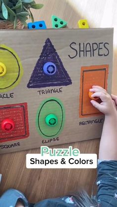 a child is playing with shapes and colors on a wooden sign that says shapes puzzle shapes & colors