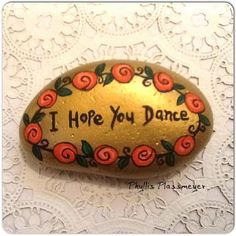 a painted rock that says i hope you dance with roses and leaves around the edge