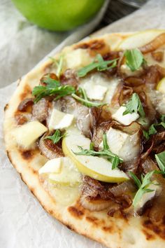 a close up of a pizza on a paper towel with an apple in the background