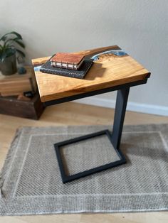 a small table with a book on it in the middle of a room next to a potted plant