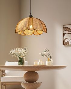 a table with flowers and candles on it in front of a light hanging from the ceiling