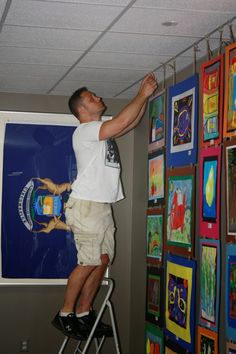 a man on a ladder painting pictures on the wall