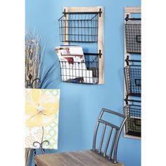 two metal baskets are hanging on the wall next to a wooden table with a chair