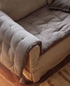 a couch that is on top of a wooden floor next to a rug and pillow